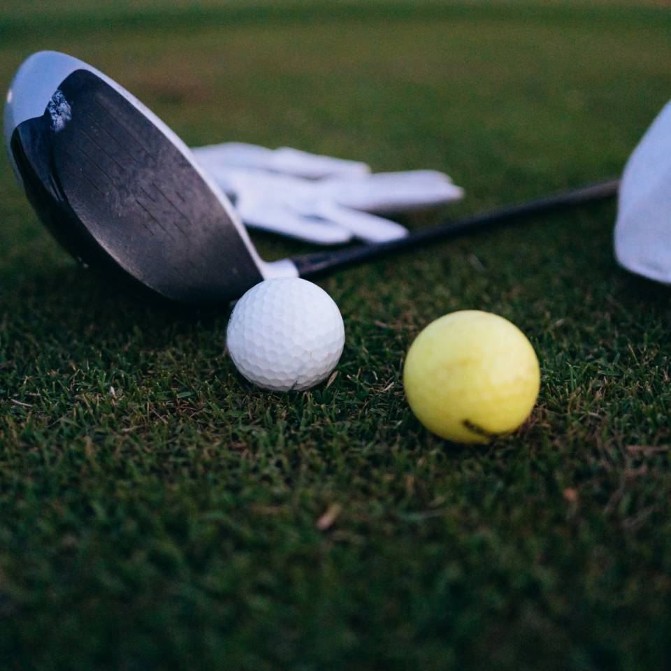 Golfschläger und Bälle liegen auf dem Green
